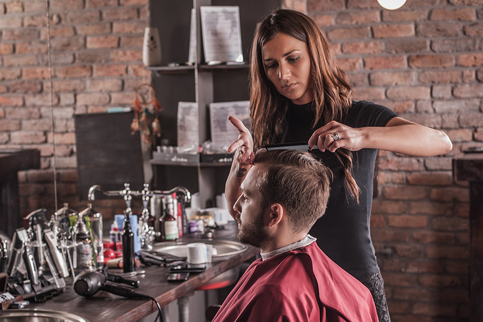 Female hairdresser hairstyle hair of man in chair